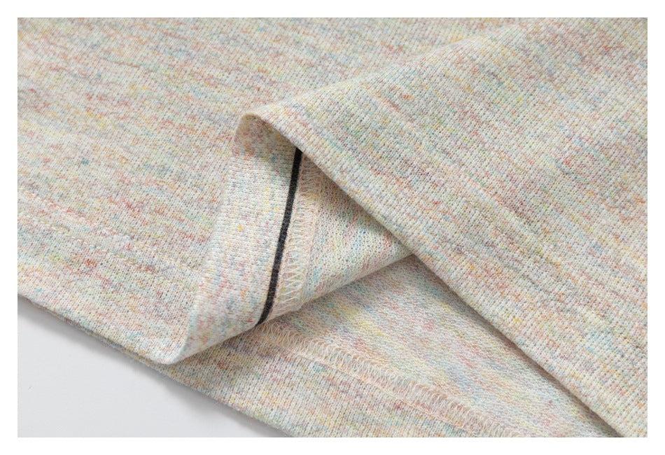 Close-up of folded T-shirt fabric showing the inside overlock seam and pastel-speckled knit.
