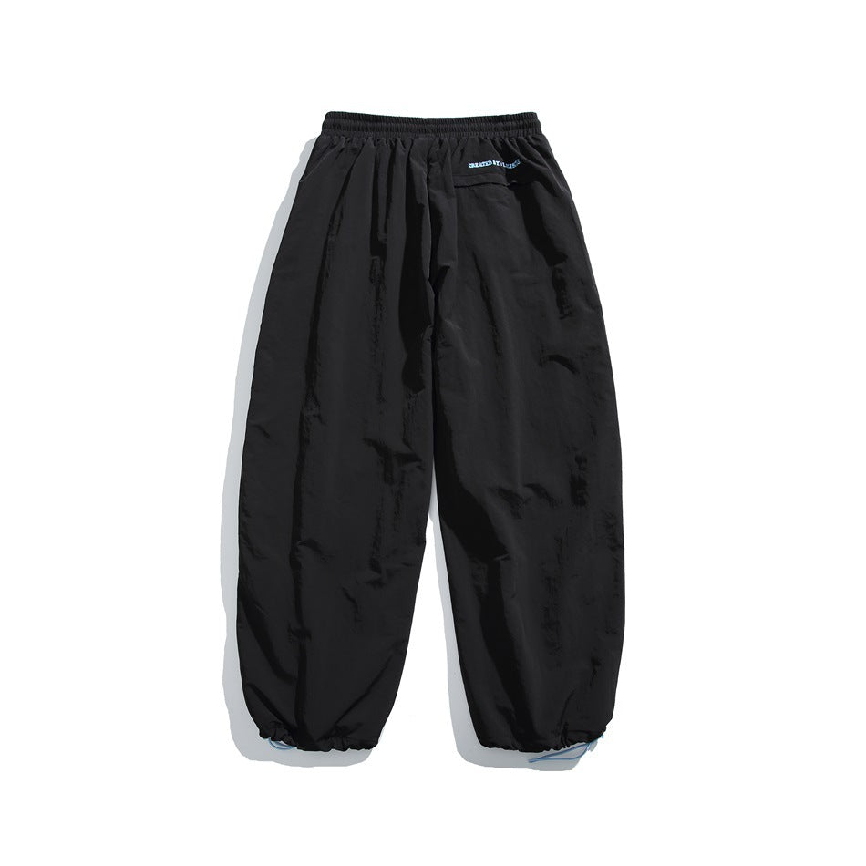 Rear view of black jogger pants with an elastic waist, a small back pocket, and gathered ankle cuffs.