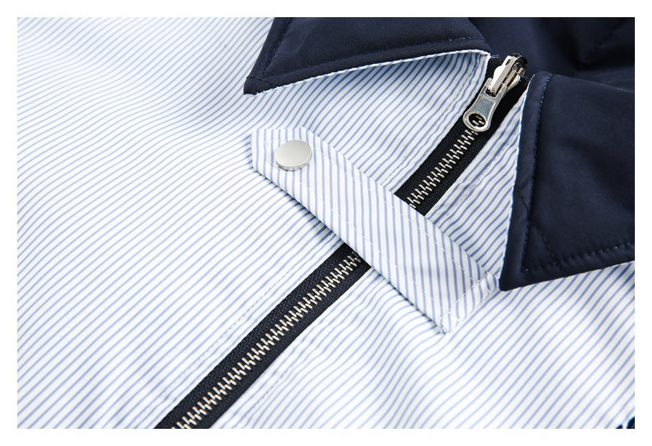 Close-up of a silver zipper and snap tab on the striped front and navy collar of a garment.