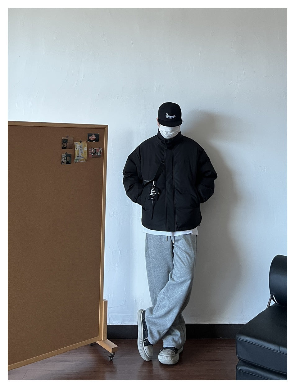 Model wearing a black padded jacket zipped closed, with a high collar and crossbody pouch.