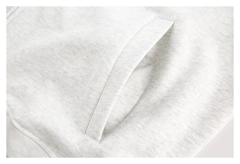 Close-up of a slanted welt pocket on light gray heathered sweatshirt fabric.
