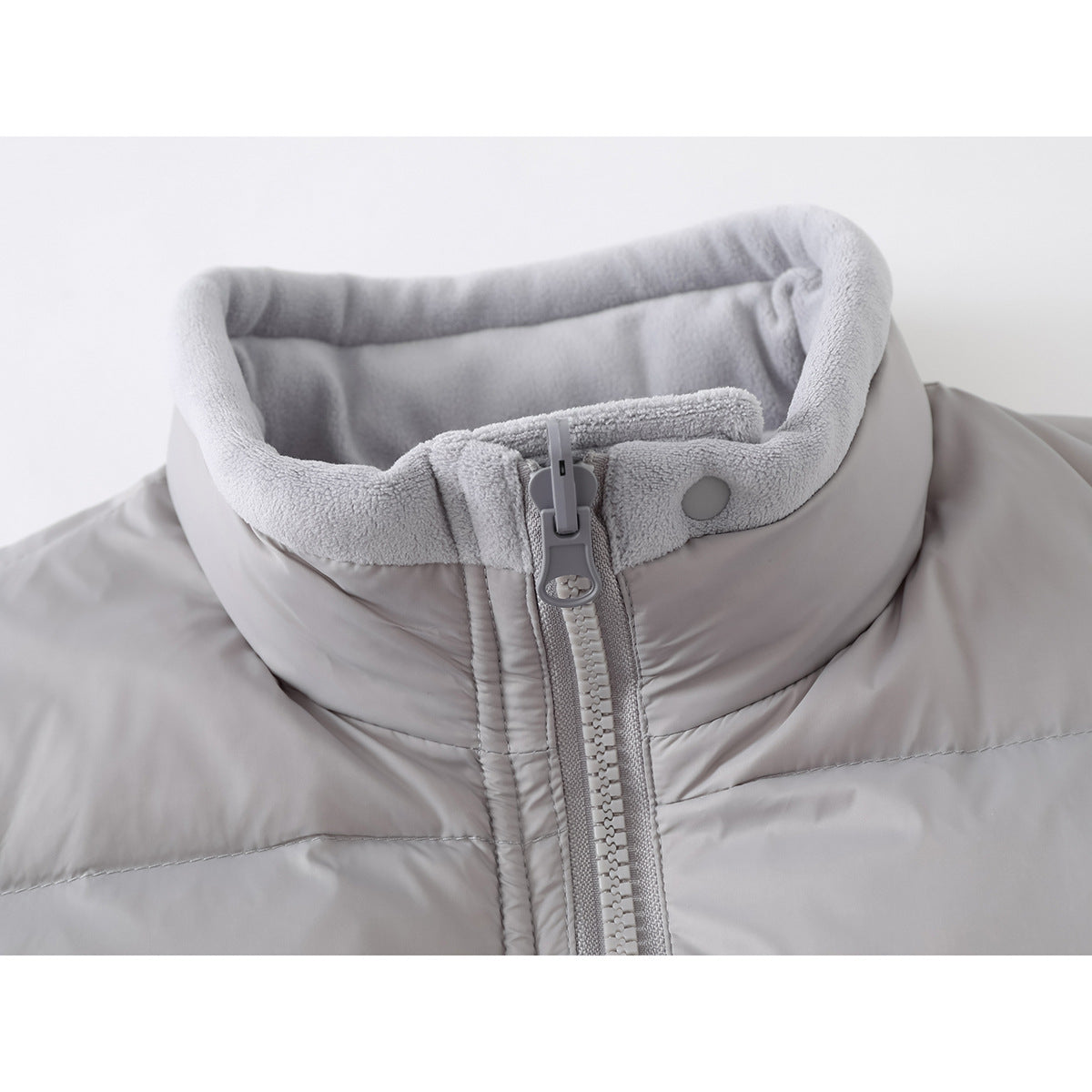 Close-up of a light gray vest collar with plush lining, snap tab, and front zipper.