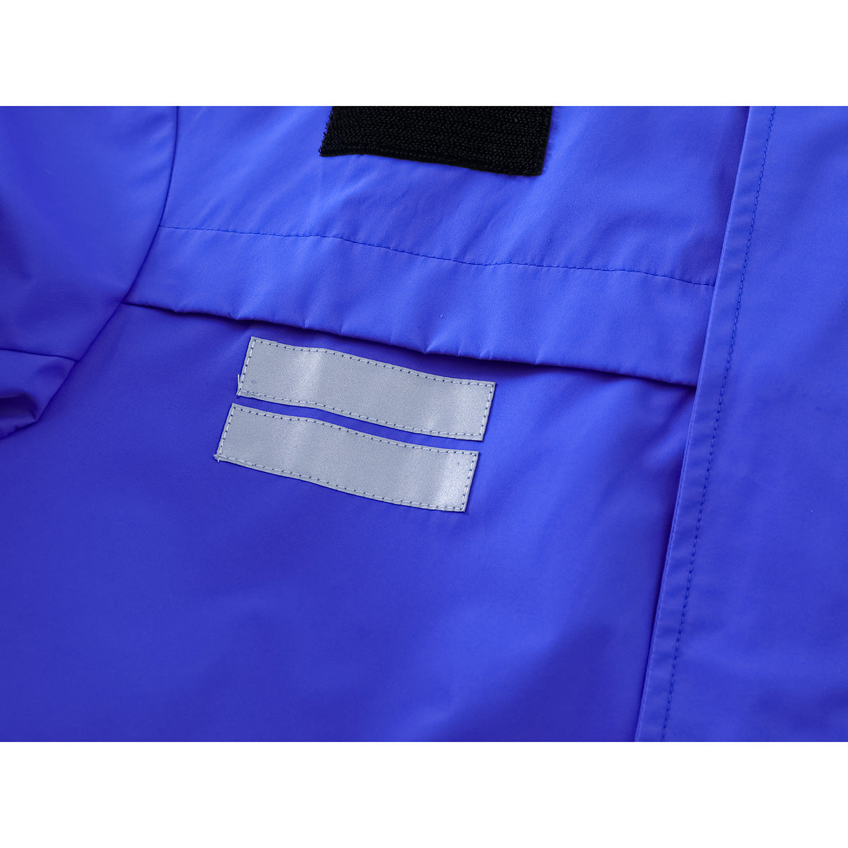 Close-up of two silver reflective strips and a black hook-and-loop patch on bright blue jacket fabric.