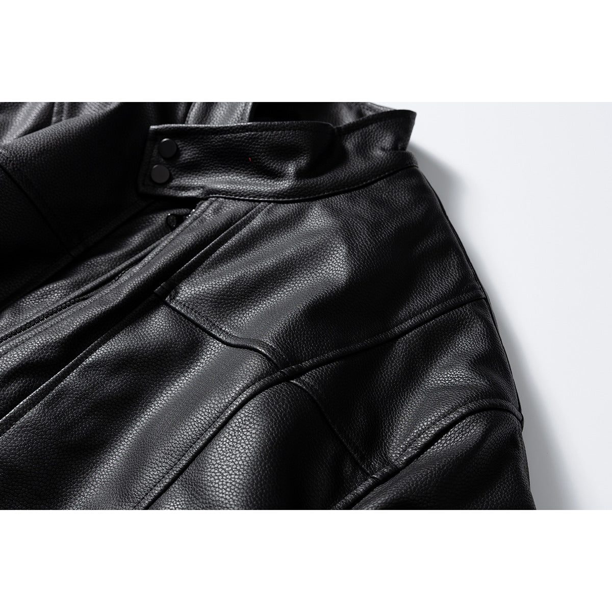 Close-up of the black jacket's snap collar, angled front seam, and curved stitched panels.
