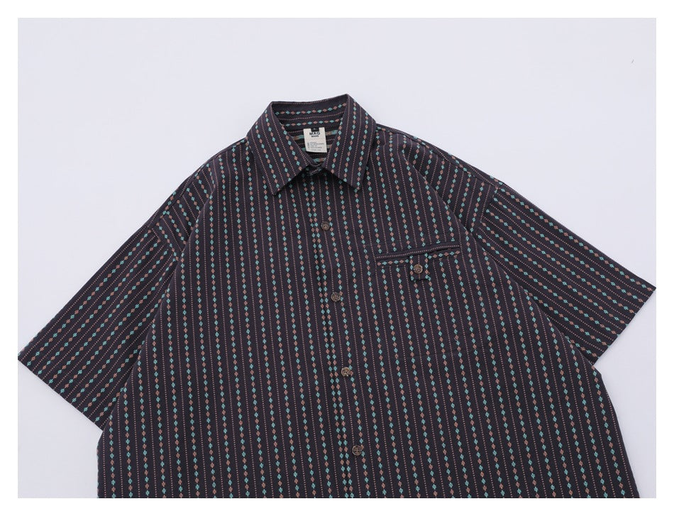 Close view of the upper front of a dark patterned shirt, showing its collar, buttons, and chest pocket.