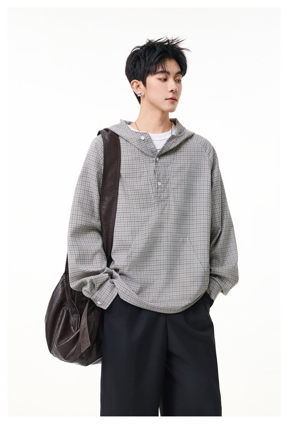 Three-quarter view of a model wearing a gray micro-check hooded pullover with a button placket and kangaroo pocket.