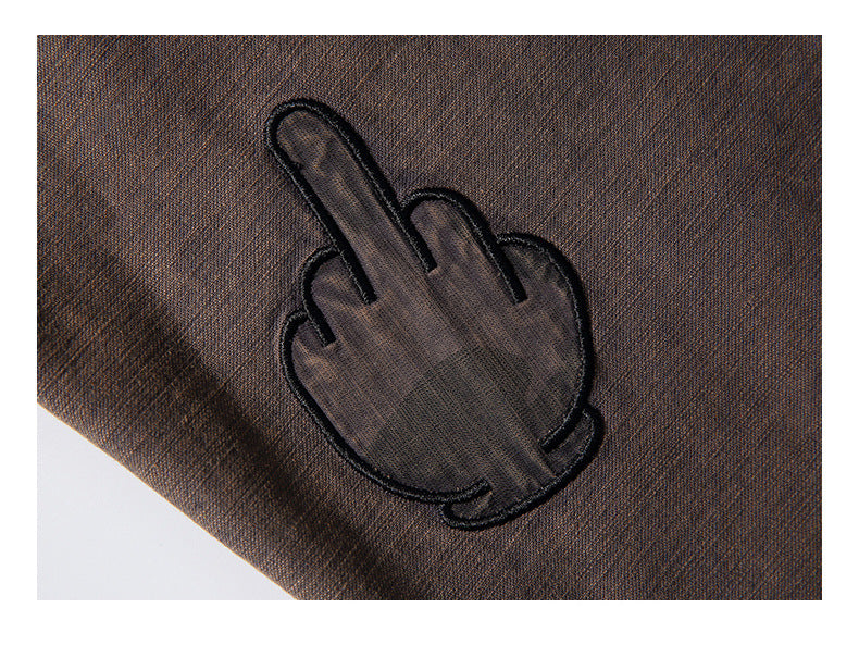Close-up of dark brown textured fabric with a black embroidered hand gesture.