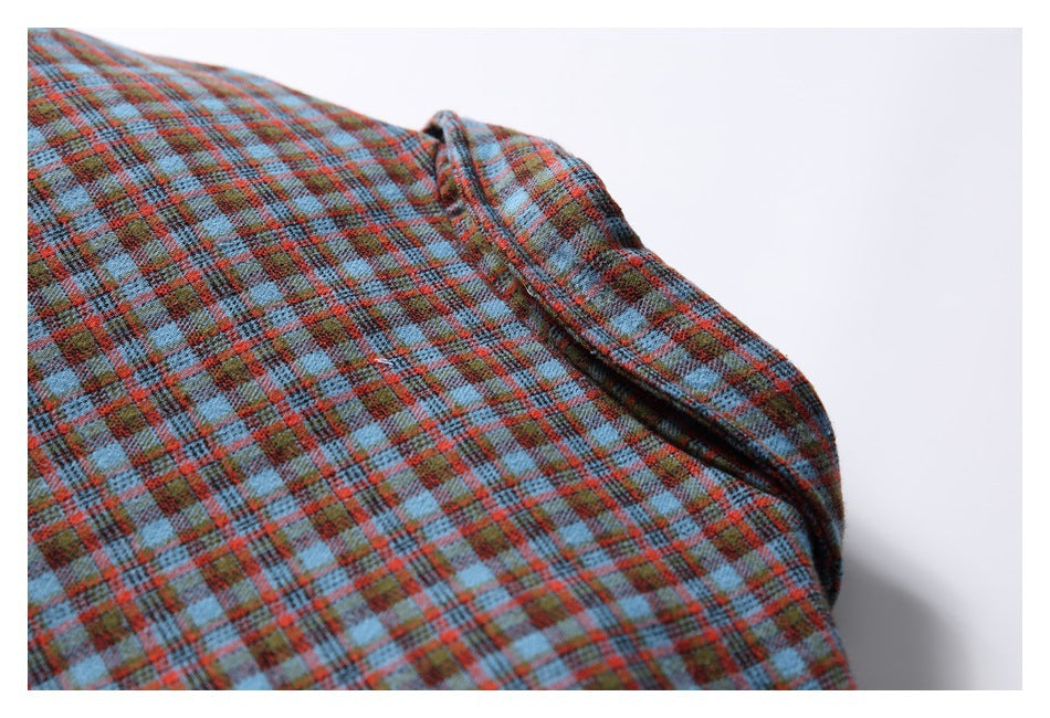 Close-up of blue, red, and brown plaid jacket fabric with a folded seam.
