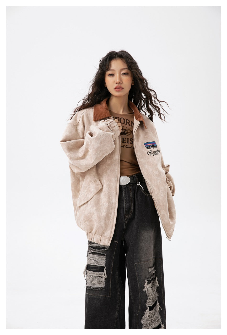 Model wearing a light beige zip jacket with a brown collar, chest embroidery, and large front pockets.