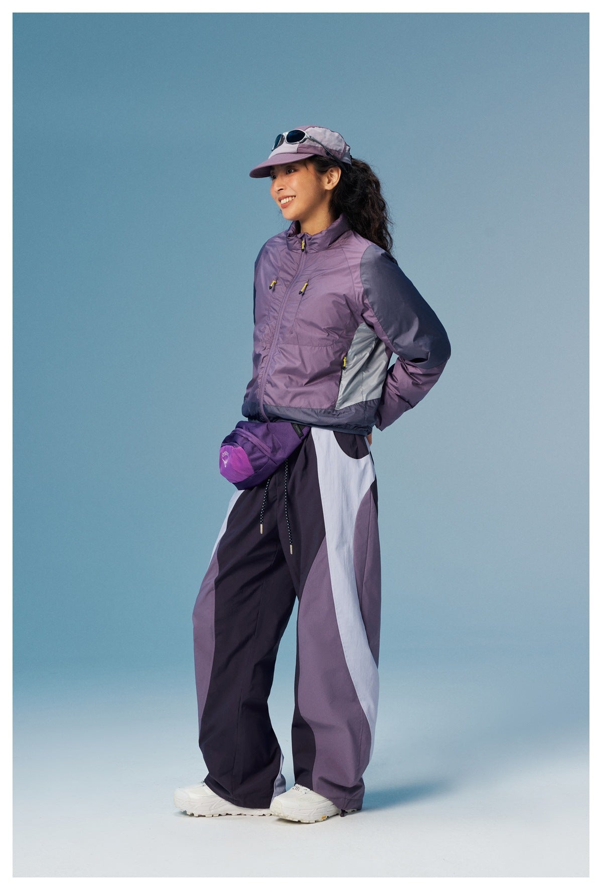 Three-quarter view of a model wearing a lavender and charcoal color-block jacket with matching wide-leg pants.