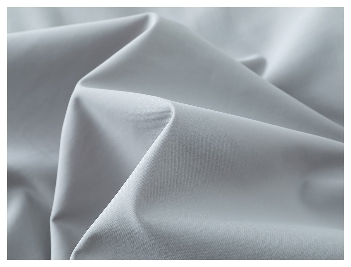 Close-up of smooth light gray garment fabric arranged in soft folds.
