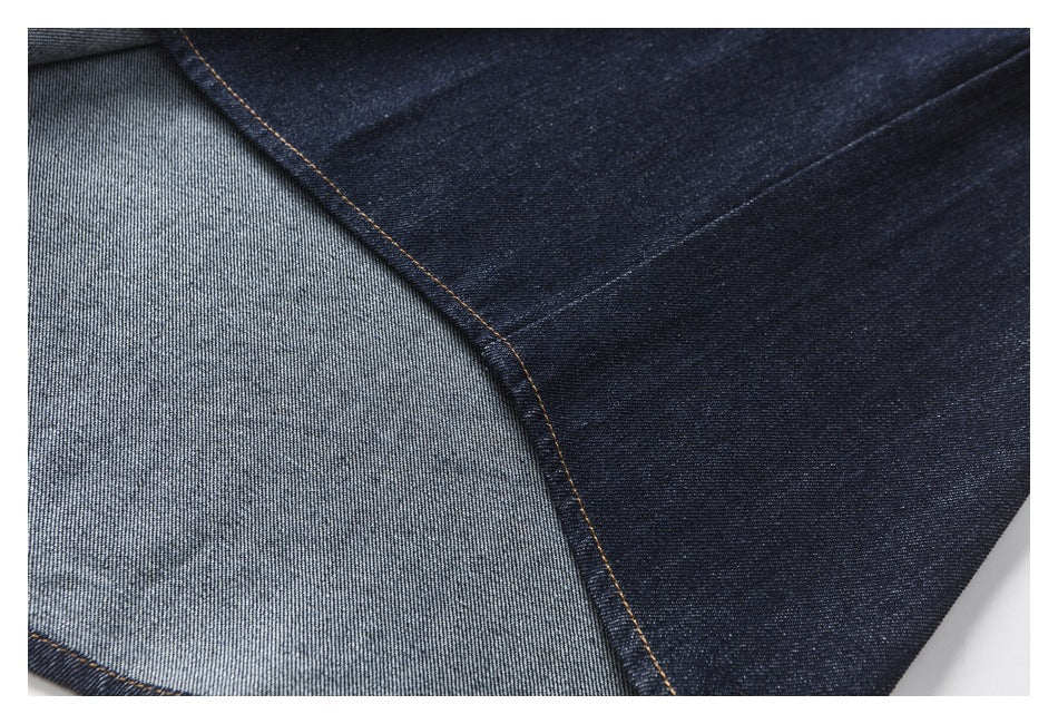 Close-up of dark indigo denim showing the lighter reverse side and tan contrast stitching.
