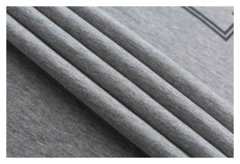 Close-up of draped gray knit fabric with a partial dark angular graphic at the upper right.