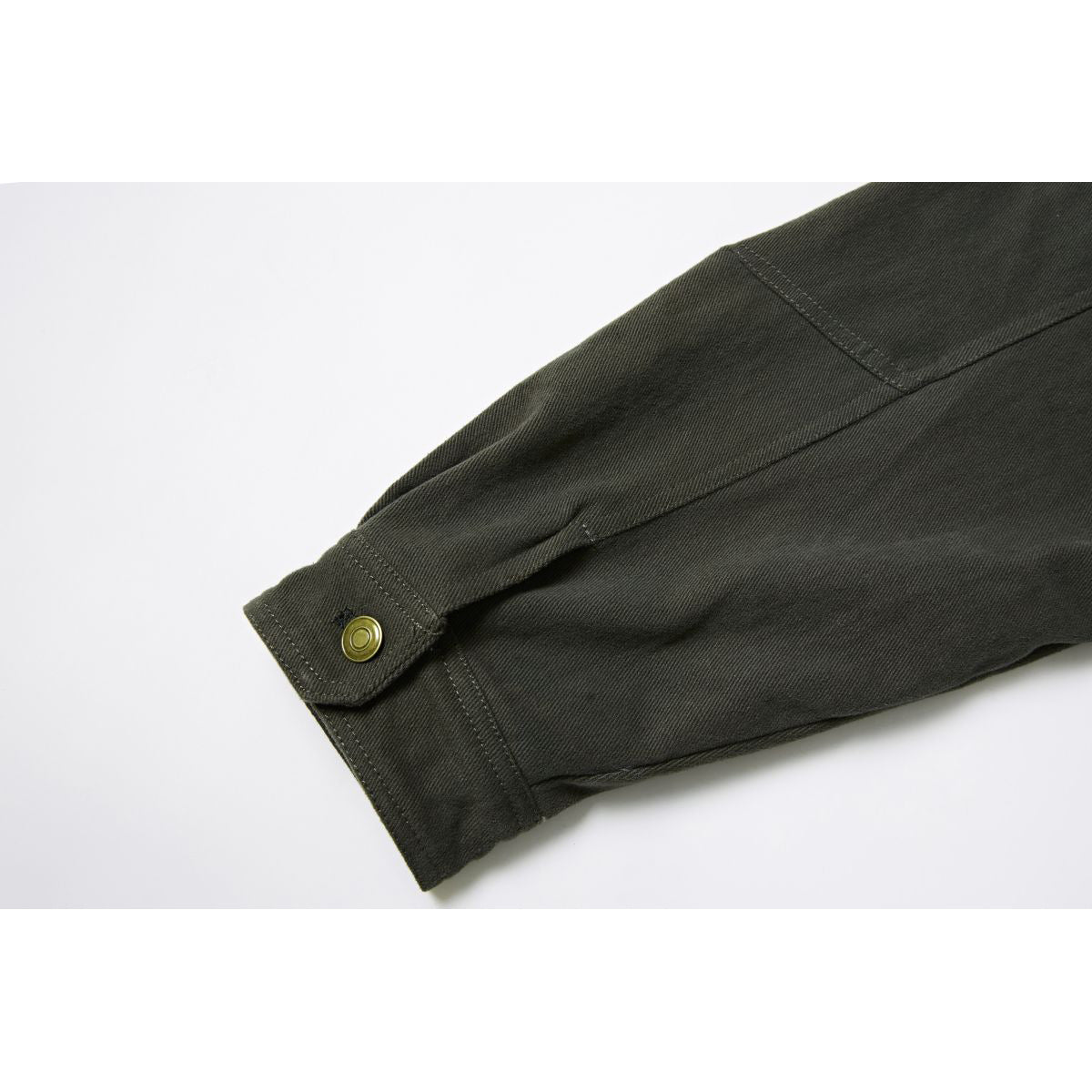 Close-up of a dark olive jacket sleeve cuff with a brass snap and visible panel stitching.