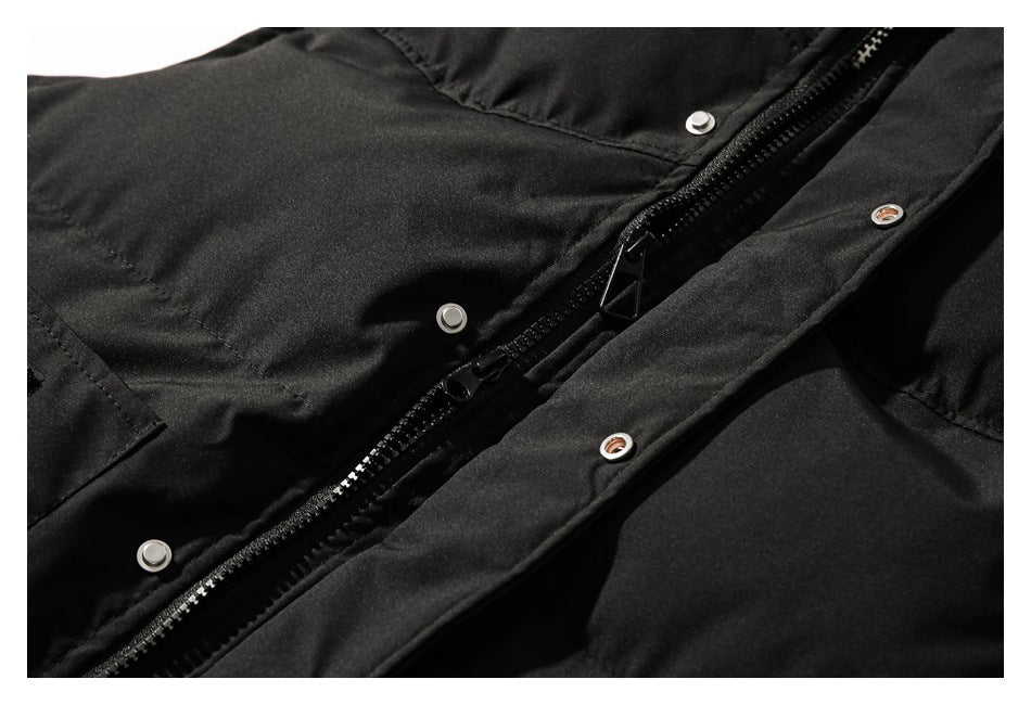 Close-up of a black garment's front zipper and snap-fastener storm flap.