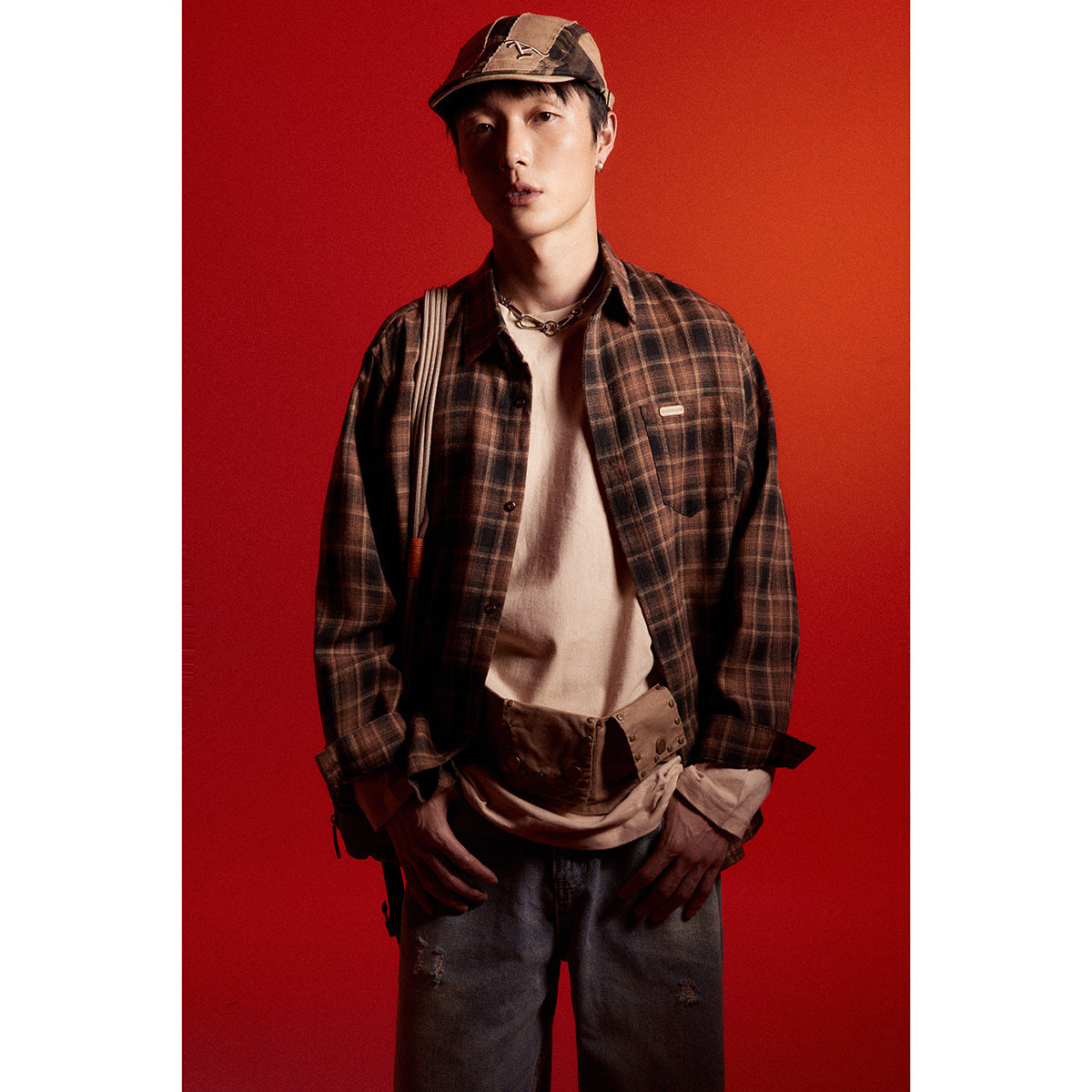 Close view of a model wearing a brown-and-blue plaid button-up shirt over a taupe top.