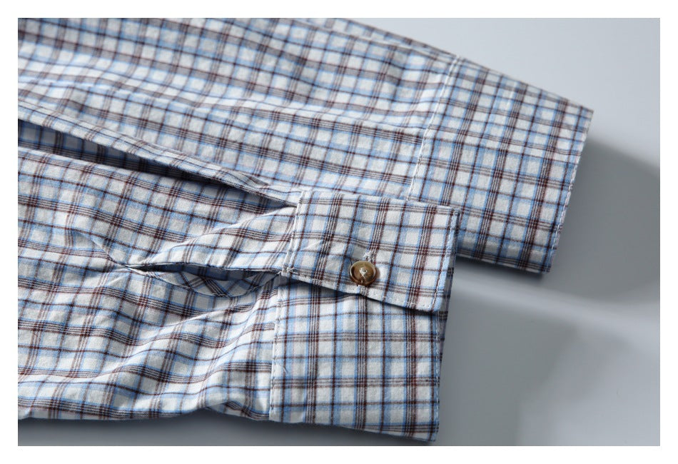 Close-up of the plaid shirt sleeve cuff with a brown button and finished edge.