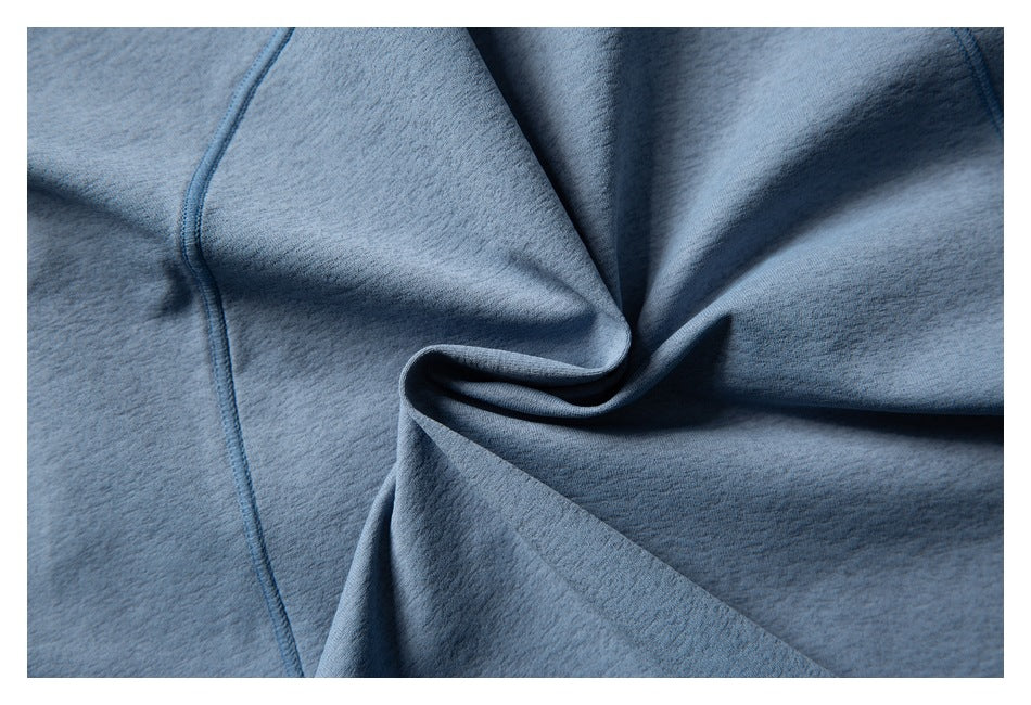 Extreme close-up of blue garment fabric gathered into folds, with a visible stitched seam.