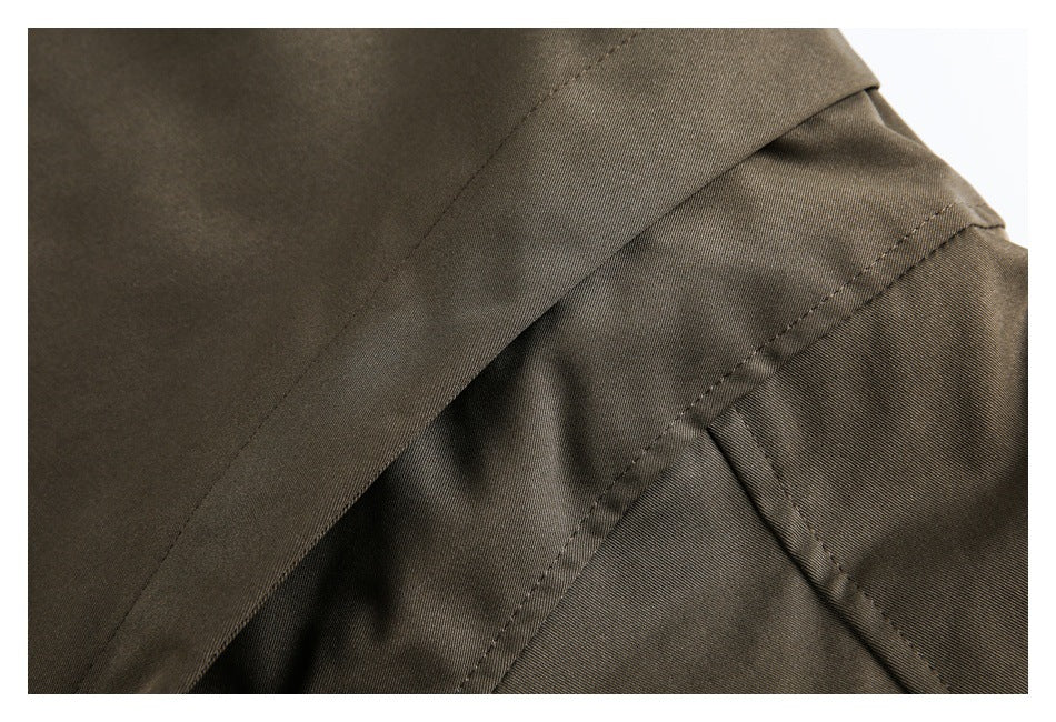 Close-up of an olive-brown garment seam with an overlapping fabric panel and stitching.
