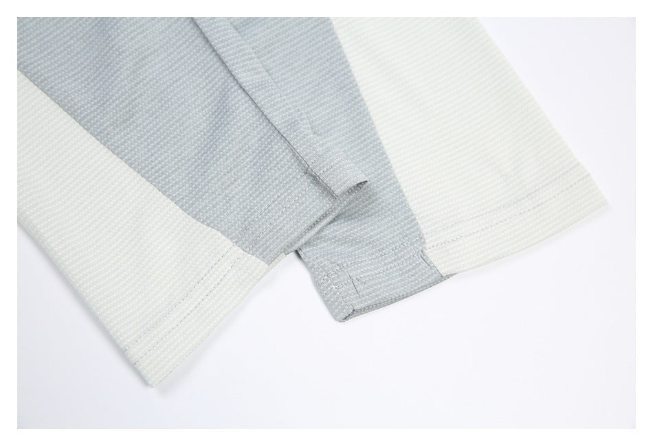 Close-up of the pale gray shirt sleeve cuff and hem with visible seam stitching.
