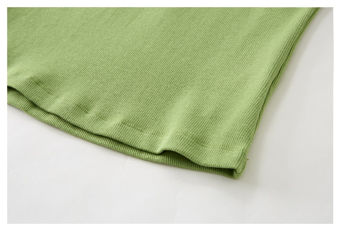 Close-up of the light green ribbed top's folded hem and stitching.