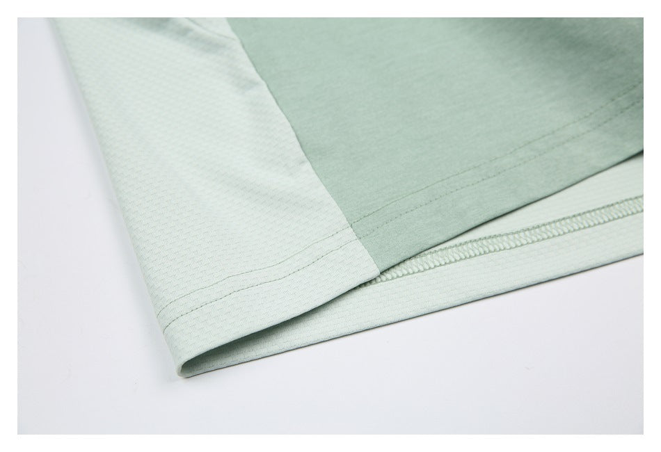 Close-up of a pale textured shirt panel meeting the mint green body at the hem.