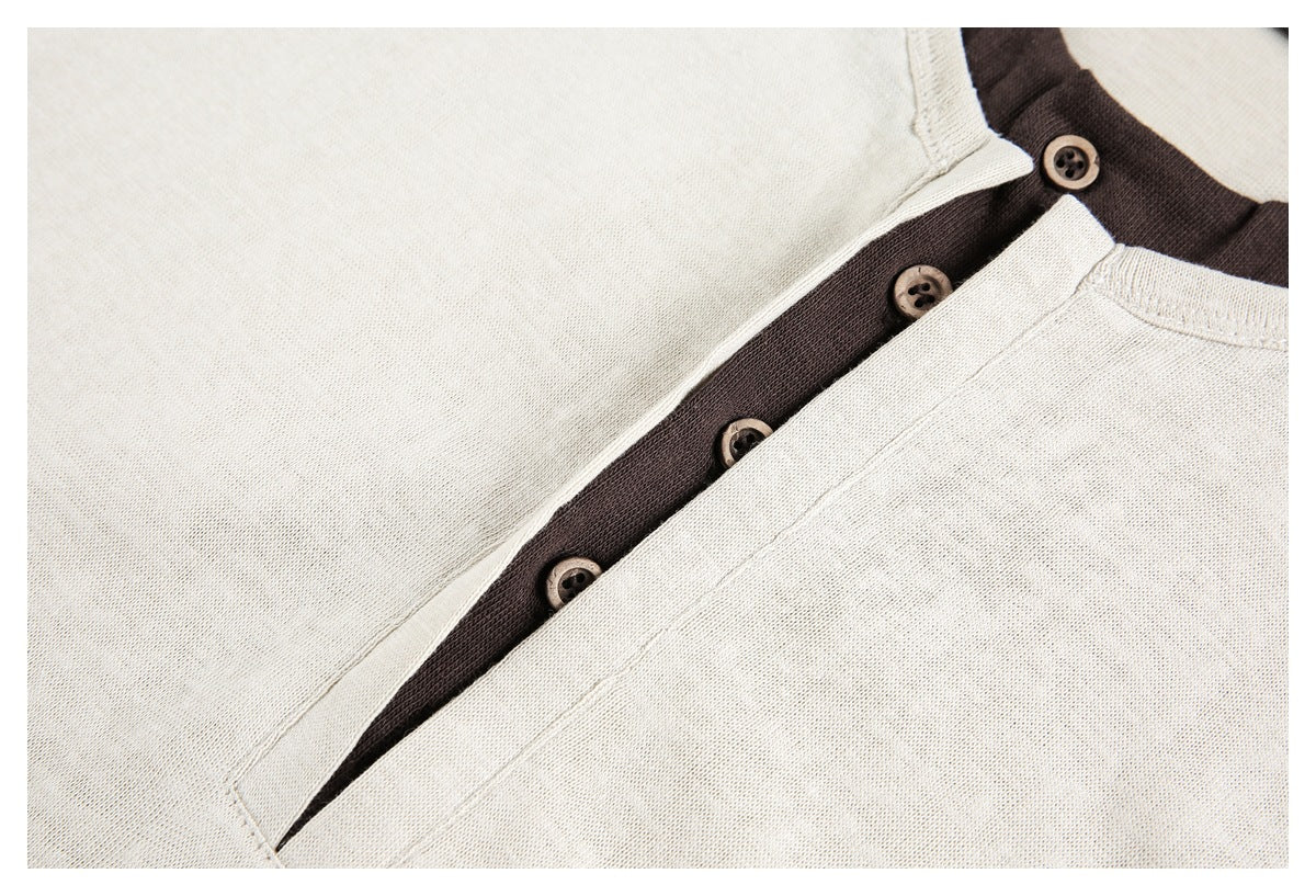 Close-up of a cream Henley placket with dark brown contrast fabric and brown buttons.