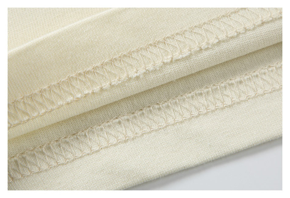 Close-up of cream garment fabric with two visible overlocked seam edges.
