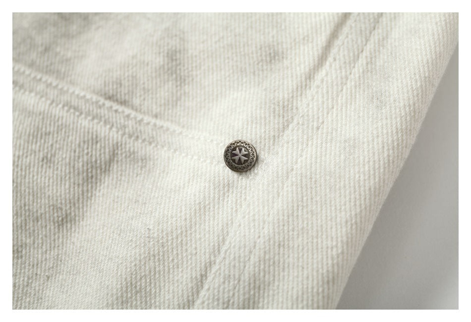 Close-up of a dark star-emblem button on cream-gray mottled trouser fabric.