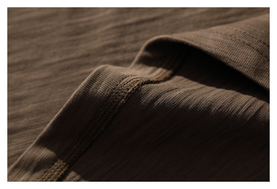 Close-up of a brown shirt's folded edge and visible stitching.