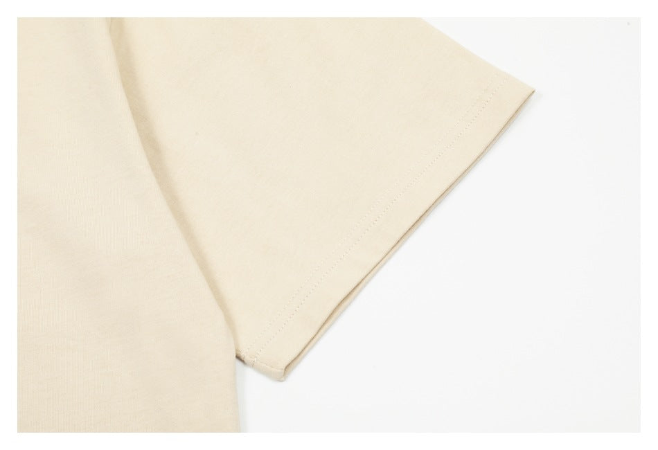 Close-up of the cream T-shirt's short sleeve and stitched cuff.