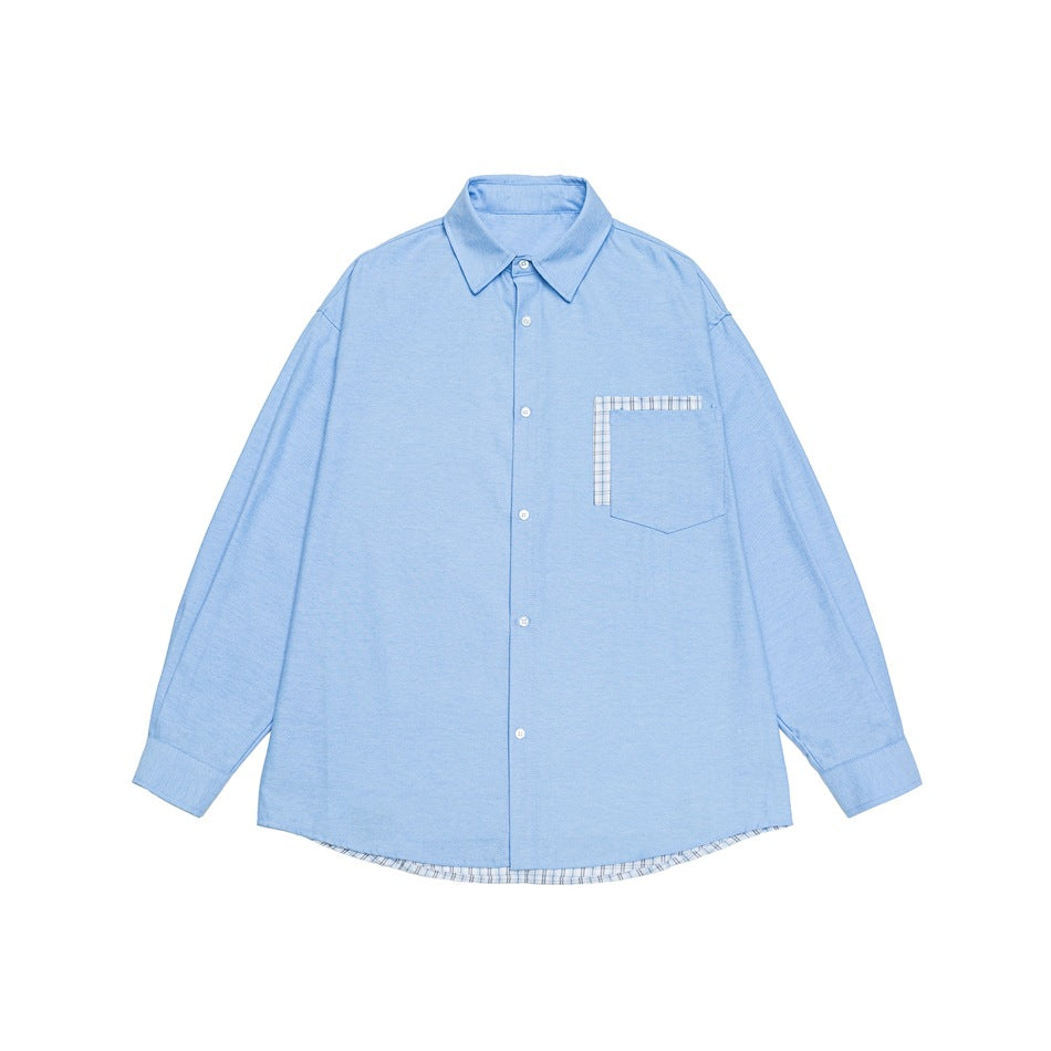 Light blue long-sleeve button-up shirt flat lay with plaid-trimmed chest pocket and plaid hem layer