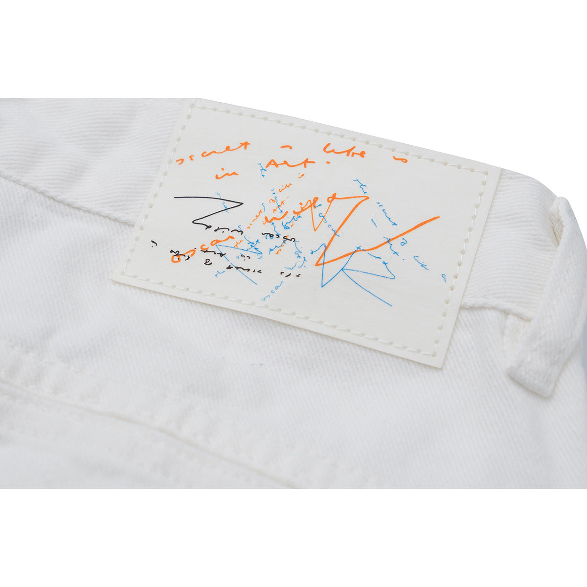 Close-up of a stitched graphic patch on the waistband of white trousers.
