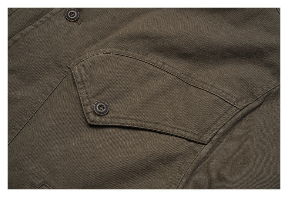 Close-up of an olive-brown jacket's buttoned flap pocket and visible stitching.