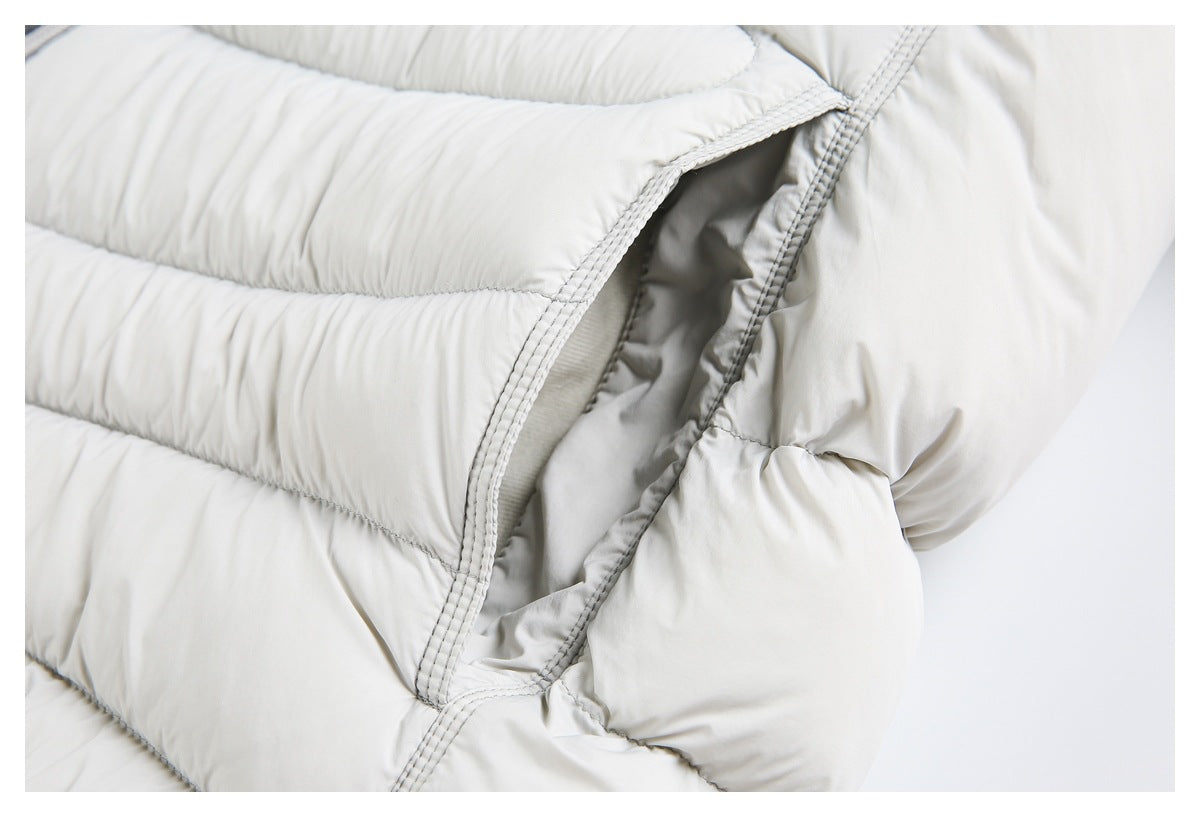 Close-up of a light gray puffer jacket's stitched side opening and padded panels.