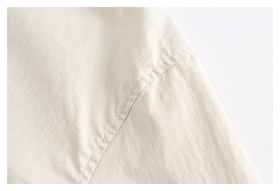 Close-up of a curved stitched seam on an ivory garment.