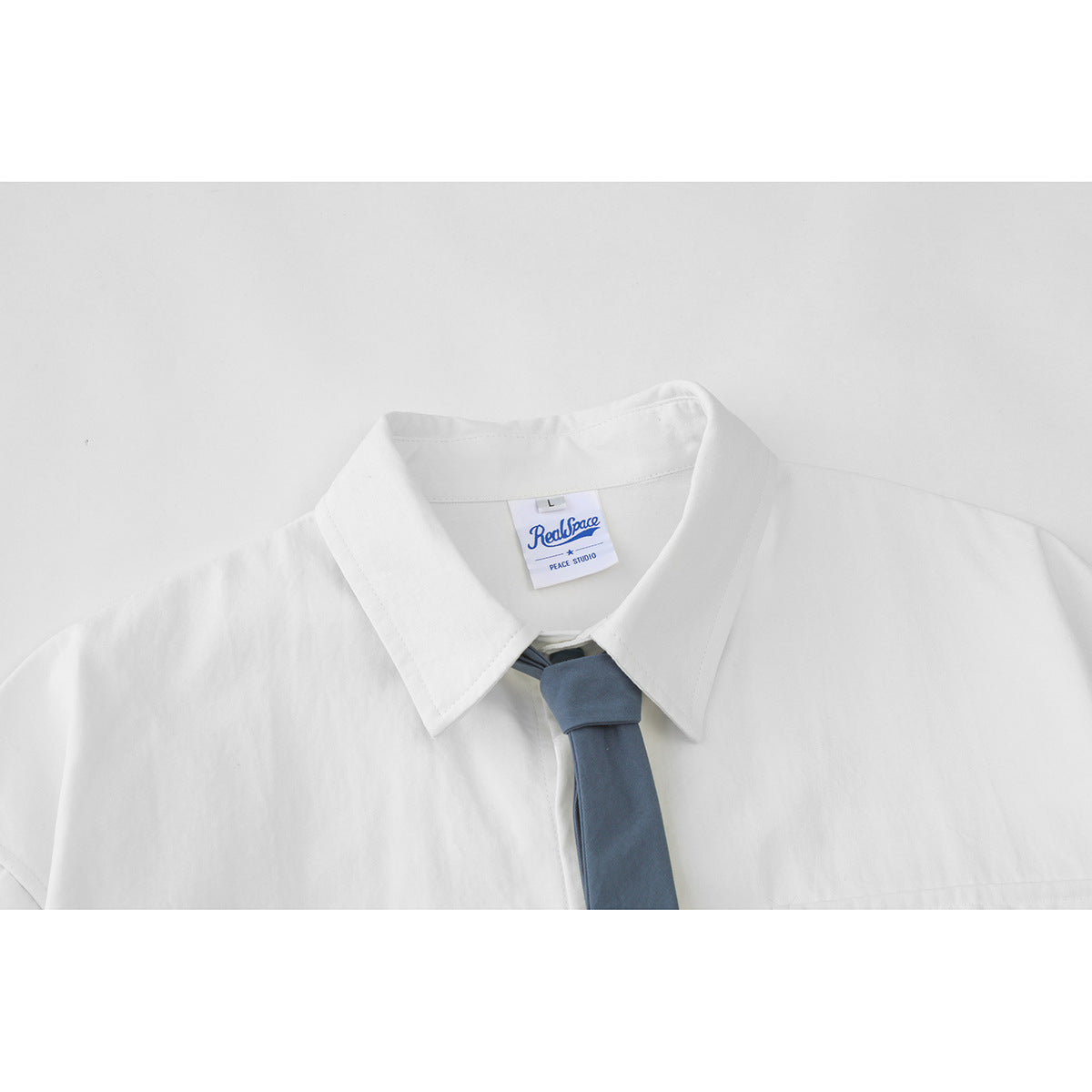 Close-up of the white shirt collar, blue tie, and sewn neck label.