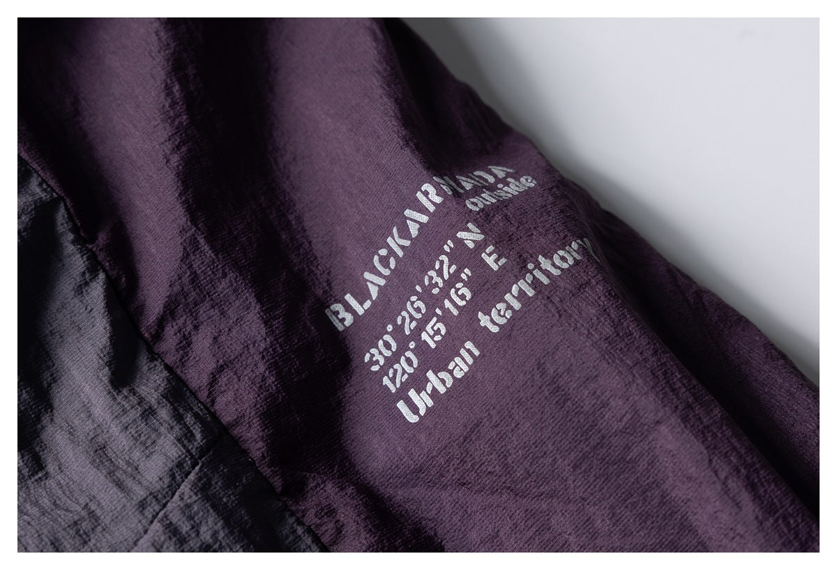 Close-up of pale English stencil-style text printed on a dark purple garment panel.