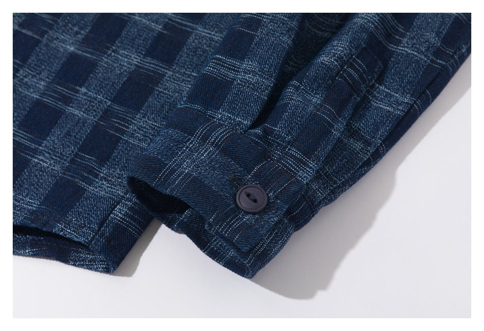 Close-up of a dark blue plaid shirt cuff with a dark button.