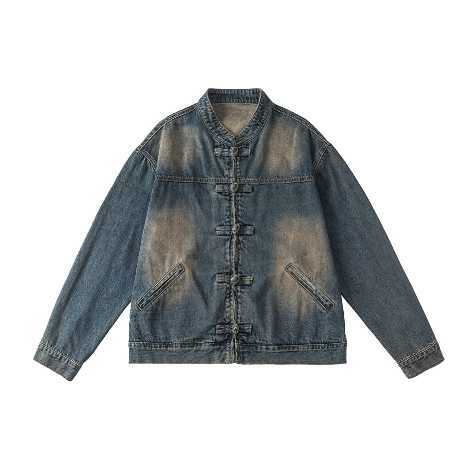 Blue washed denim jacket flat lay with stand collar, five knotted frog fasteners and tan faded patches
