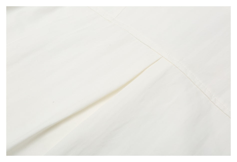 Close-up of off-white fabric with a diagonal fold and stitched seam.
