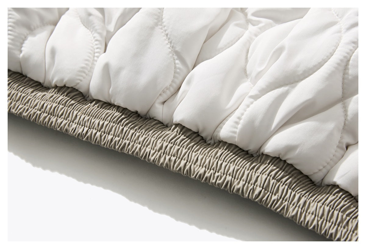 Close-up of the white quilted jacket lining gathered above a beige elastic hem.
