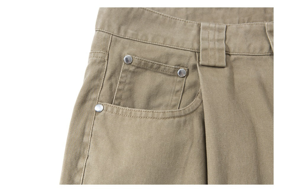 Close-up of khaki trousers showing a front pocket with silver rivets and a belt loop.