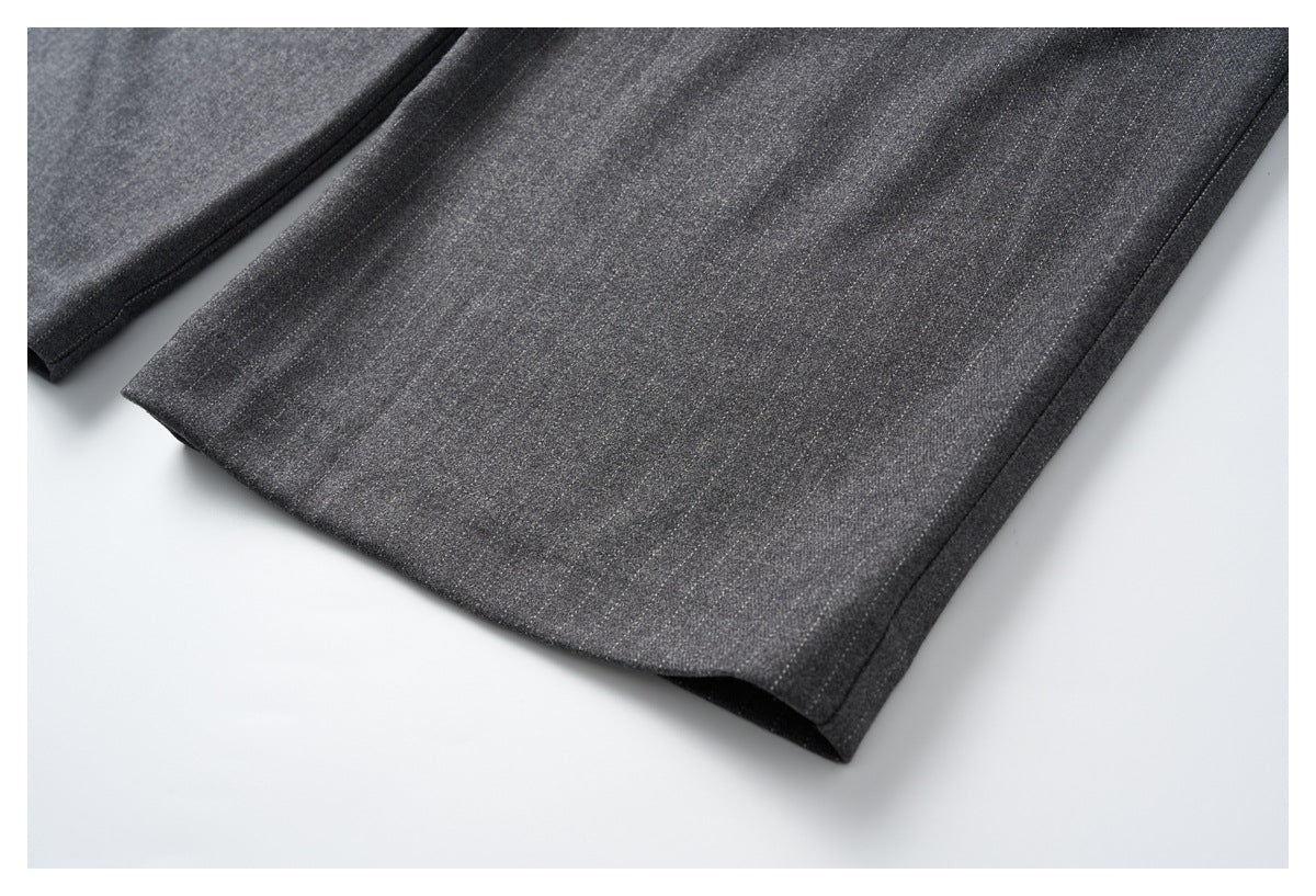 Close-up of the straight hem and edge stitching on charcoal gray trouser legs.