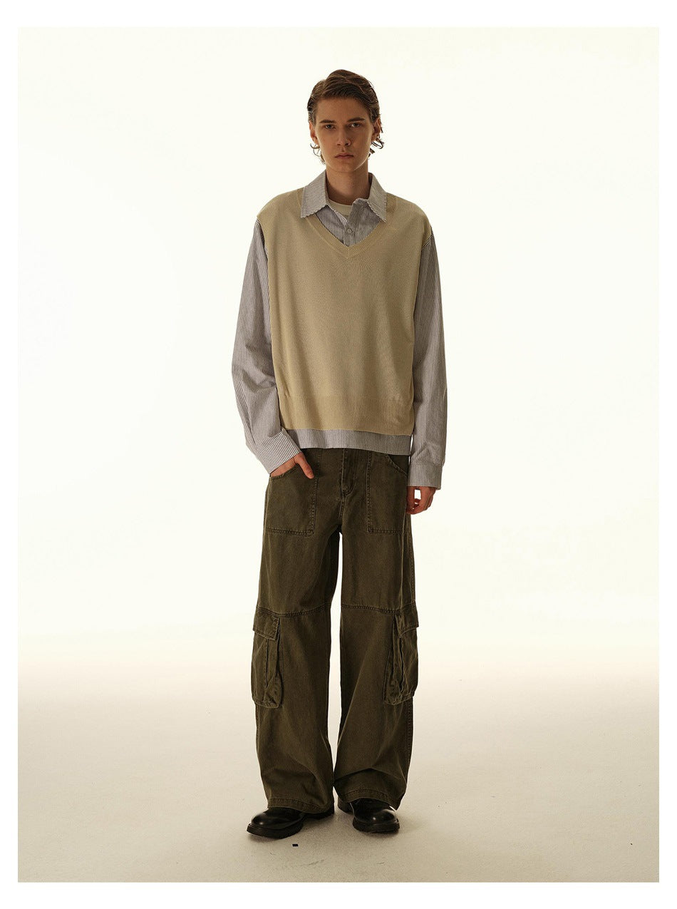 Full-length view of a model in a striped shirt with a tan V-neck knit panel, olive cargo pants and black shoes