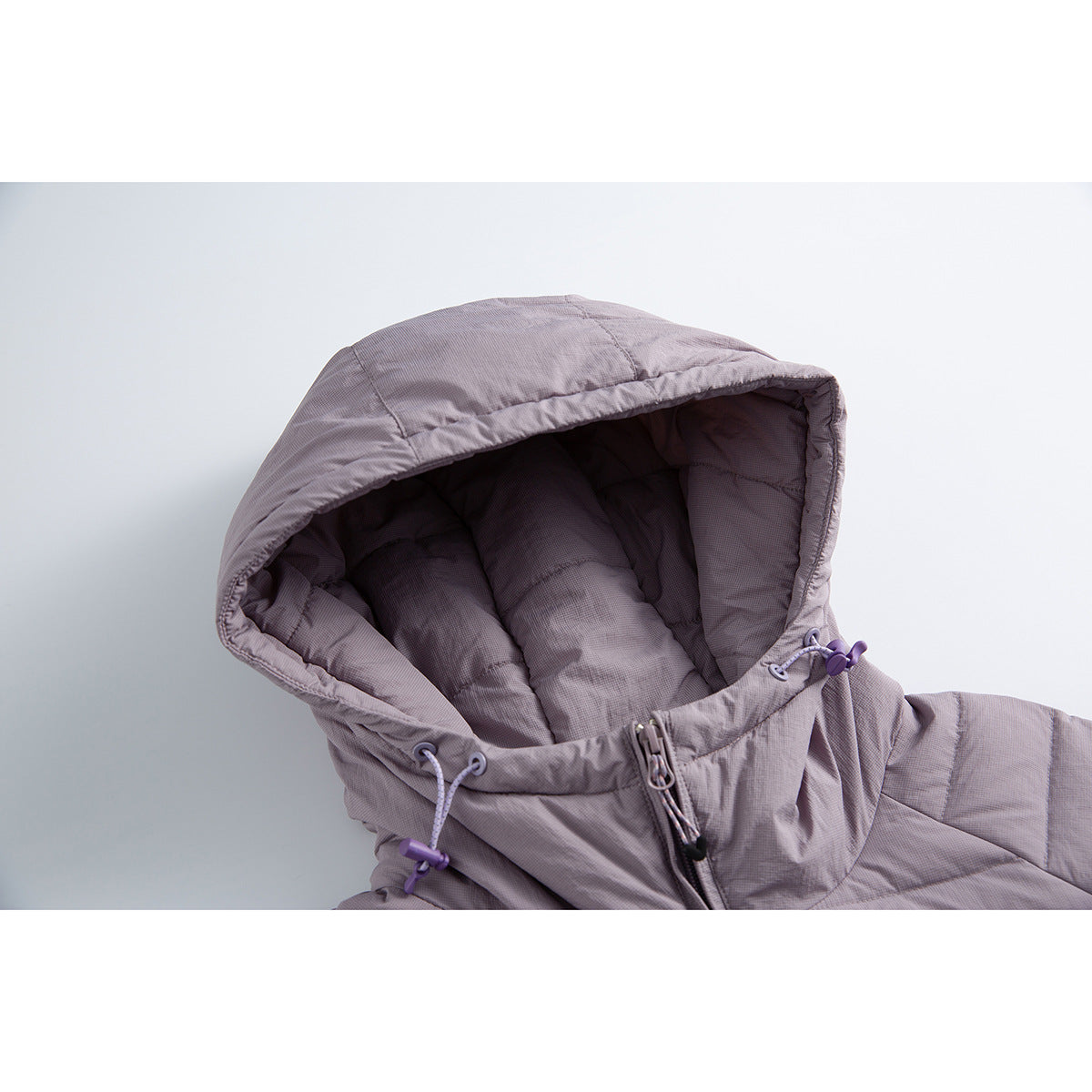 Close-up of a lavender-gray quilted jacket hood with padded lining, drawcord toggles and front zipper.