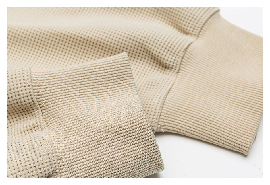 Close-up of the beige knit jacket's ribbed cuff and sleeve seam.