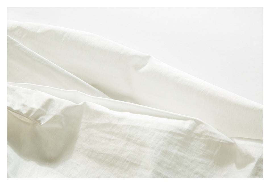 Close-up of white garment fabric with a long folded edge and visible stitching.