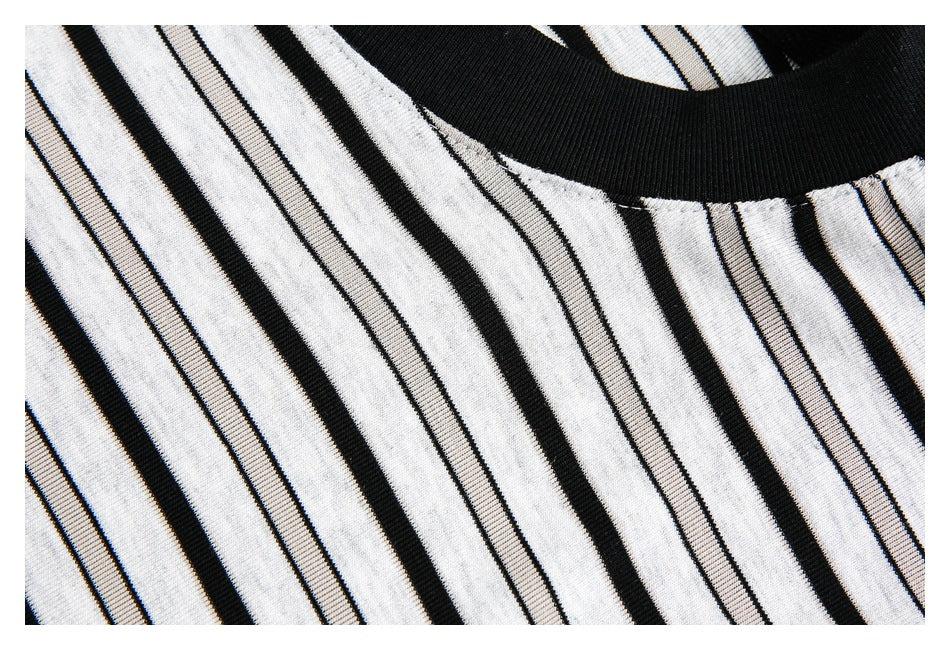 Close-up of the black ribbed neckline and alternating wide and fine black stripes on a white shirt.