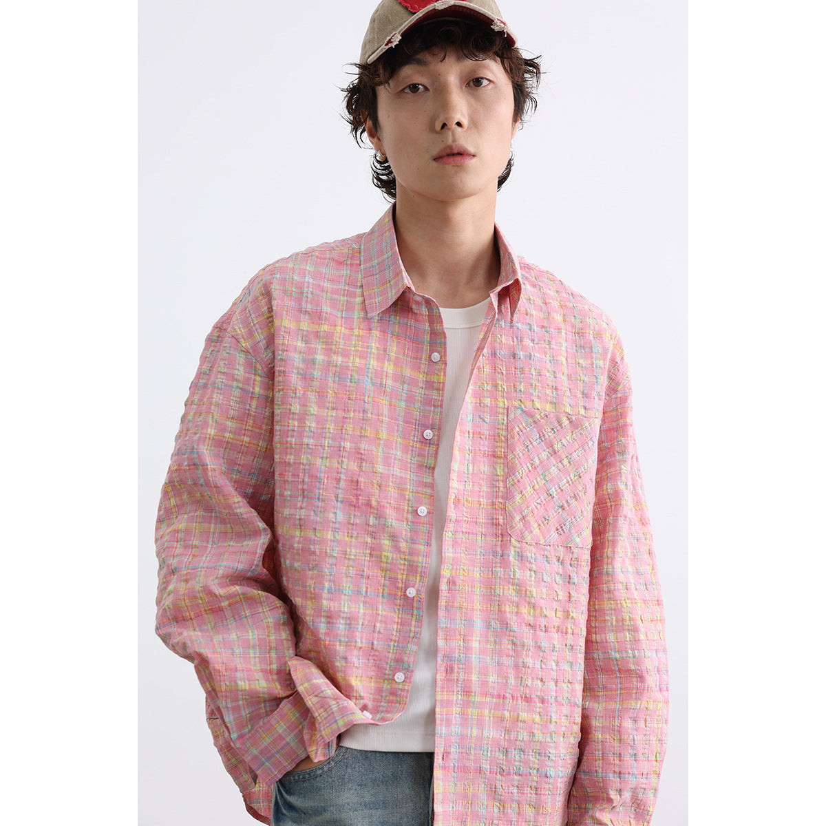 Model wearing a pink multicolor plaid button-up shirt with a chest pocket over a white tee.